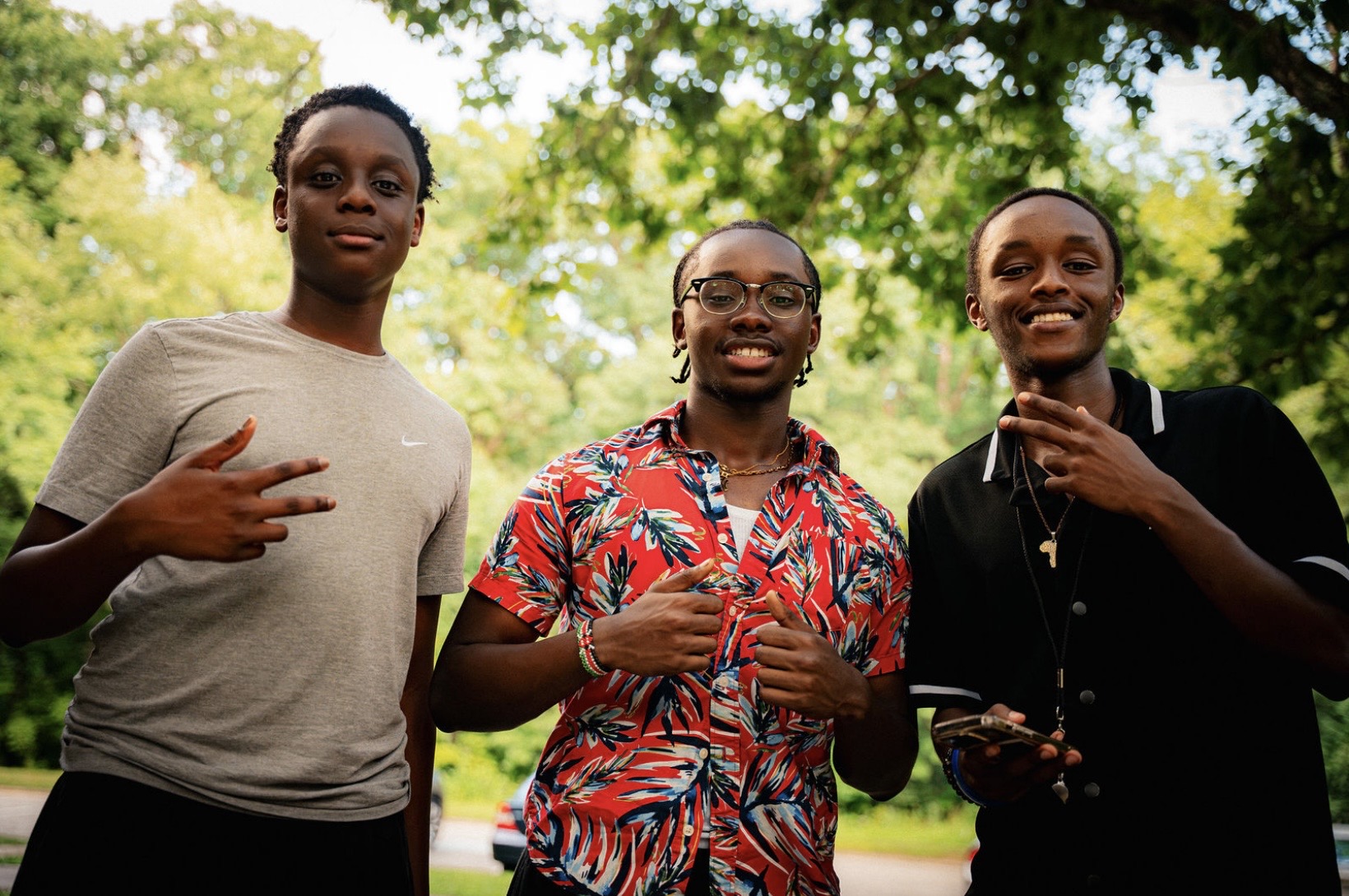 Three friends pose beneath the trees
